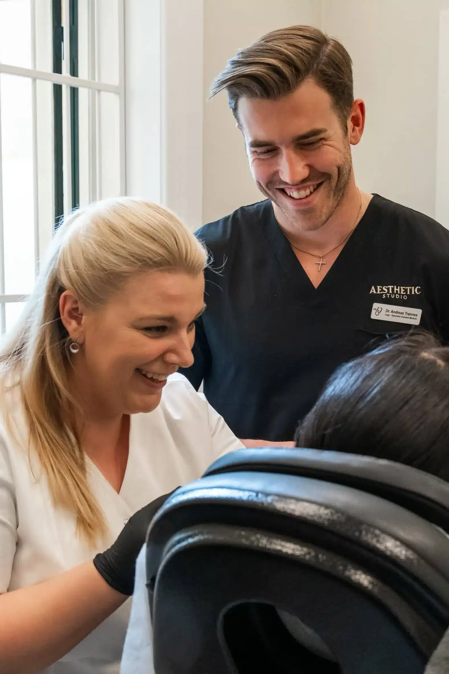 Instruktør og kursdeltakere følger behandling i praksis under sertifiseringskurs i estetiske injeksjonsbehandlinger.